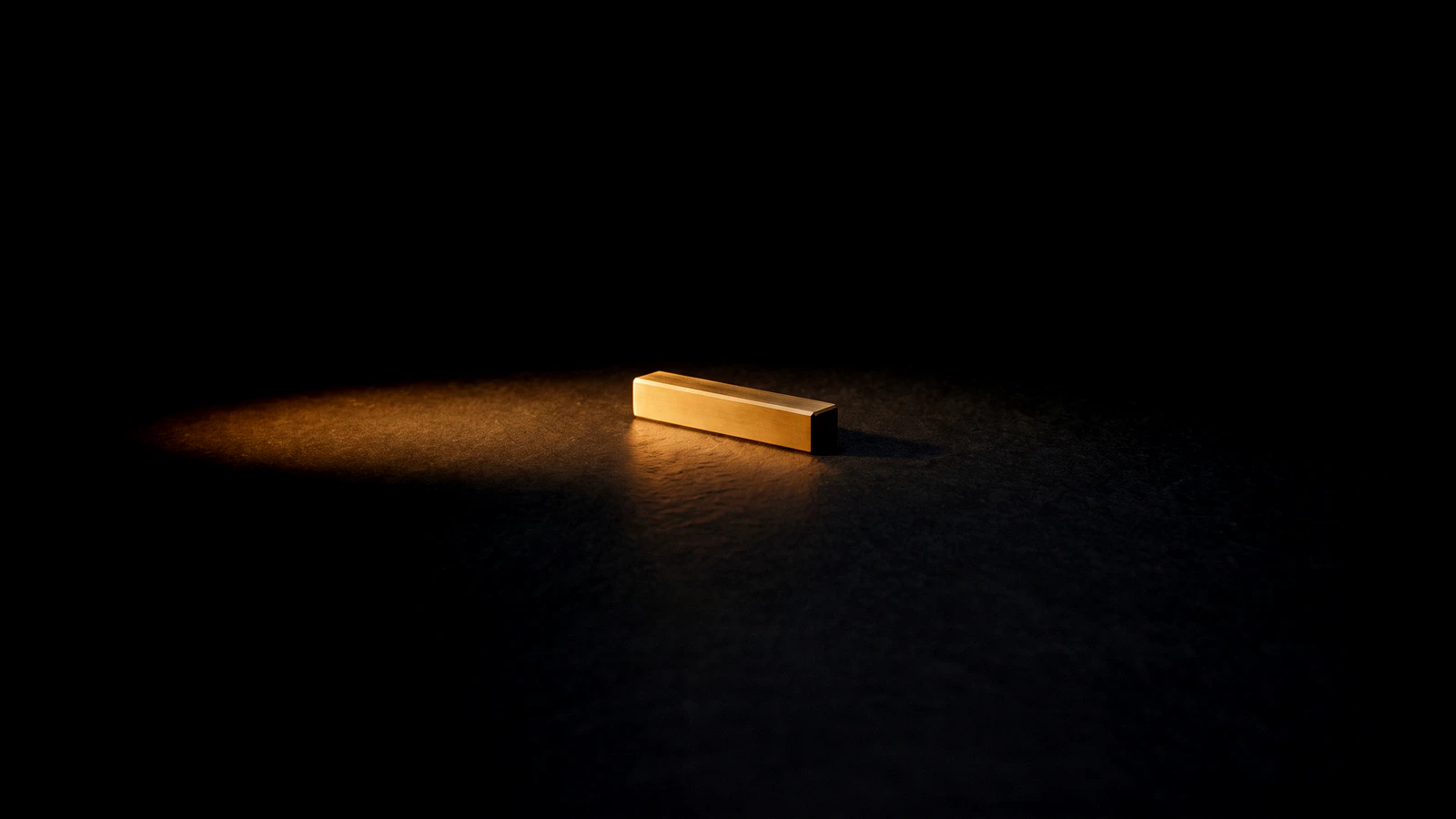 One small brass bar alone in a pool of light on a wide empty floor.