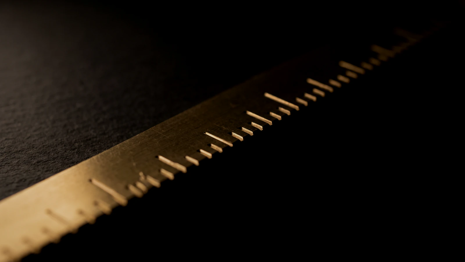 A brass rule receding into black, its graduation notches unnumbered.